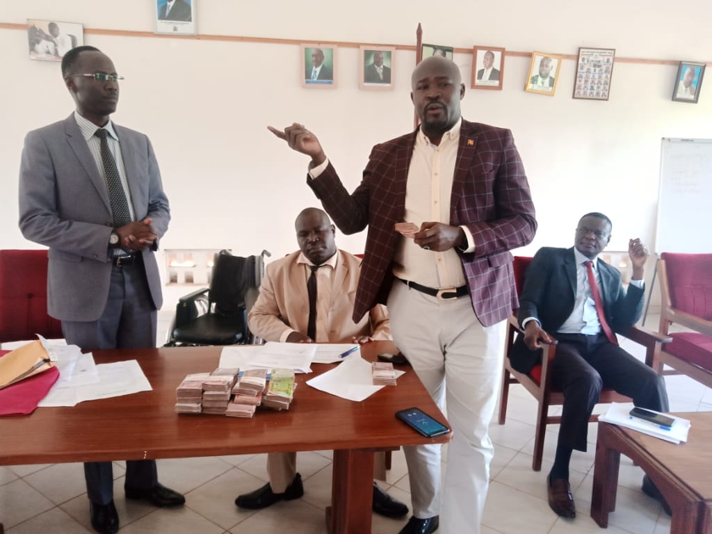 Dokolo North MP, Paul Amoru hands over the funds to Resident District Commissioner Lawrence Egole