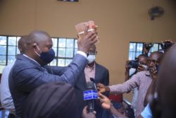 Jinja West MP(L) Hands Over 20M COVID Cash to Town Clerk Ochen (R) on Tuesday