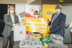 MTN CEO, Wim Vanhelleputte (L) displays the contents of the relief kits that will be distributed to the flood victims in Kasese district