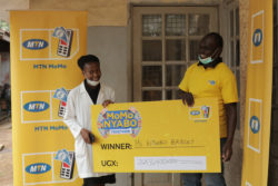 MTN's Emmanuel Thoryek (R) presents Bridget Kitimbo's dummy cheque. Her money was sent directly to her phone and that of her beneficiary