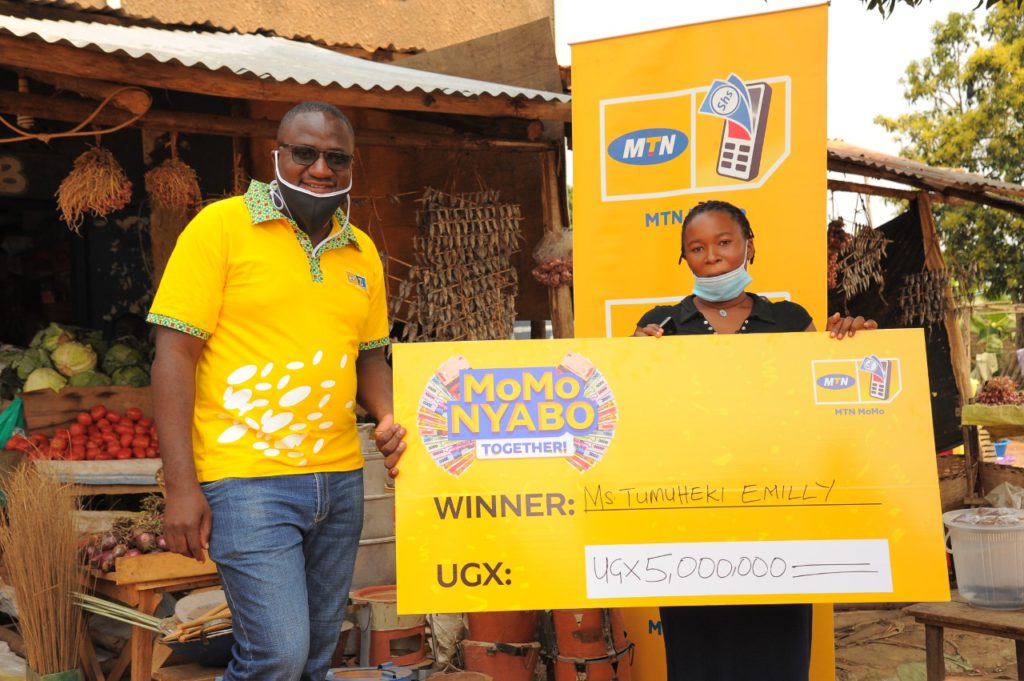 MTN's Jimmy Ssempuuma (L) hands over Emily Tumuheki's cheque