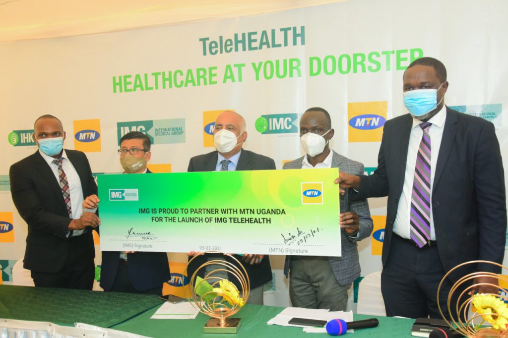 MTN Uganda's Chief Marketing Officer, Somdev Sen (2L) poses for a photo with the IMG staff after signing the partnership agreement
