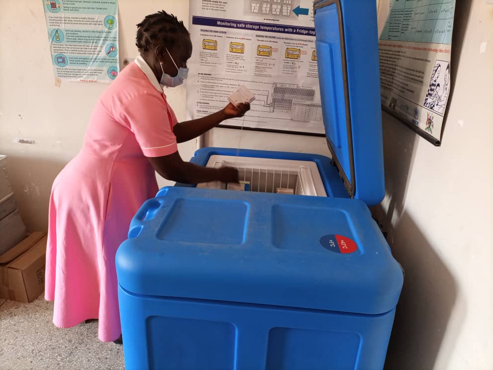 A nurse at bidibidi health centre iii checks for a vaccine in the solar vaccine fridge donated to the health centre by MTN