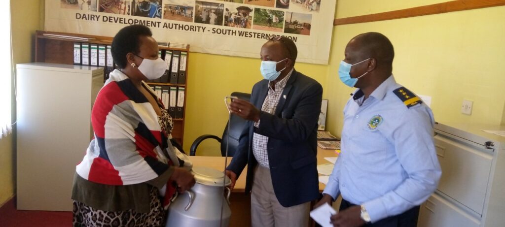 Dr . Micheal Kansiime handing over a milk-can and a plunger to one of the farmers