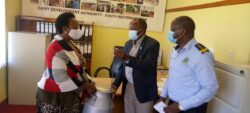 Dr . Micheal Kansiime handing over a milk-can and a plunger to one of the farmers