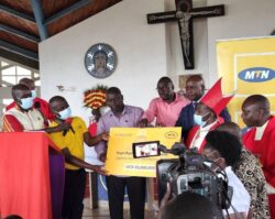 MTN's Joseph Bogera hands over a dummy cheque to the Fort Portal Diocese