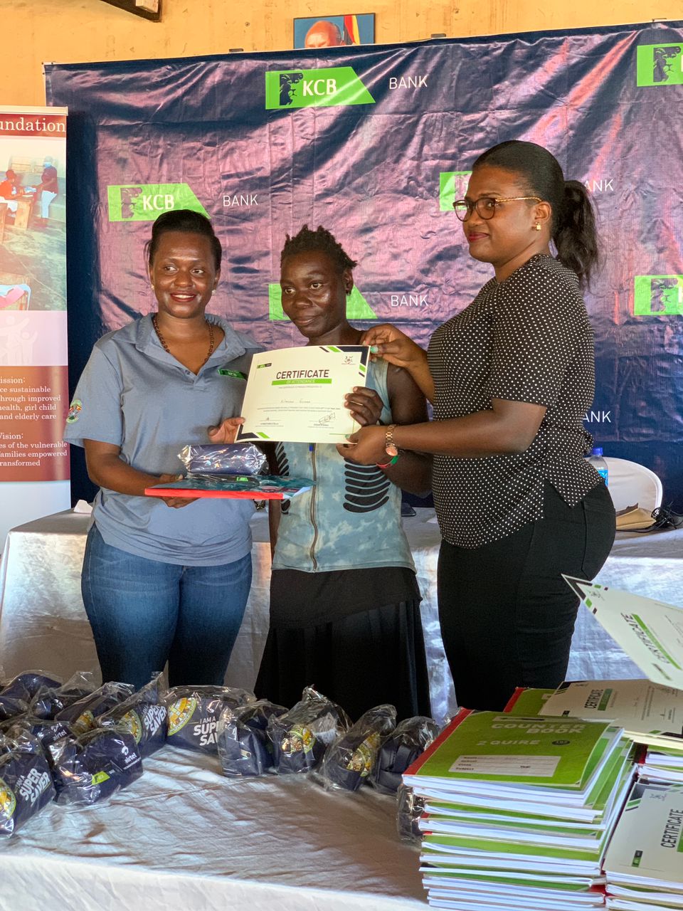 Sylvia Sashuha, (L), Marketing Manager, Corporate and Business at KCB Bank Uganda, Senorita Nabafu, (R) a Board Member at Burgess Foundation Uganda handing over a certificate to one of the trainees.