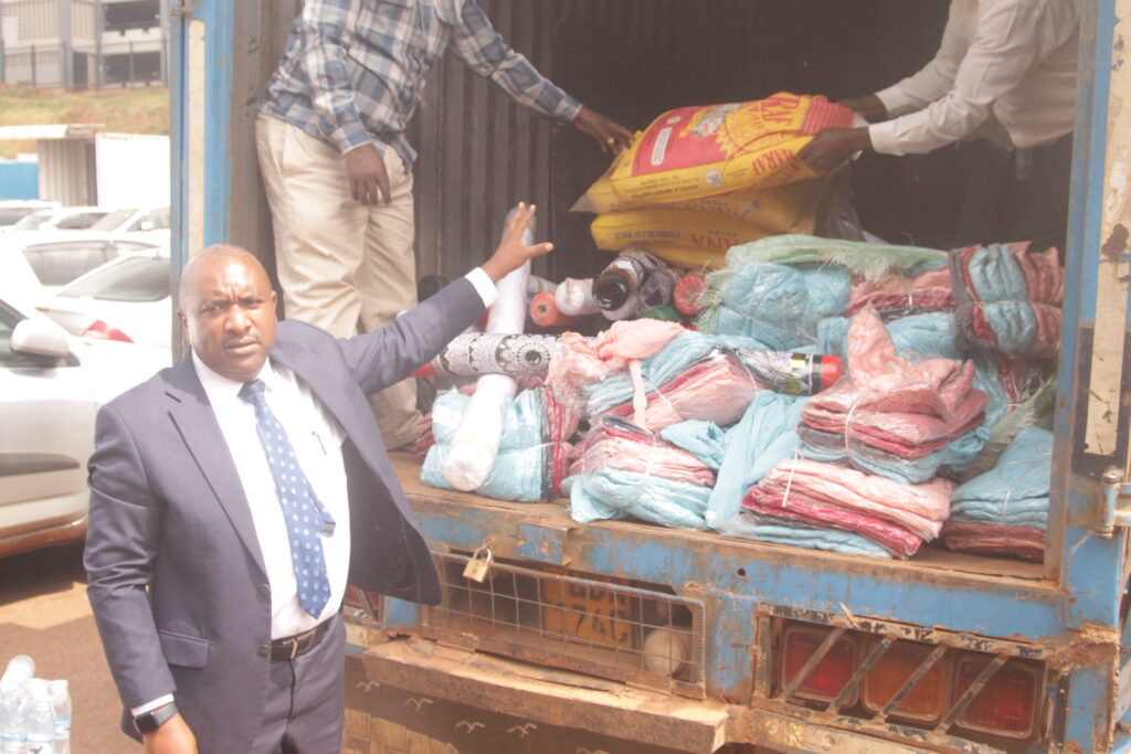 Asst Commissioner Enforcement Julius Nkwasire showing revealing the consealed goods that were found in the intercepted truck