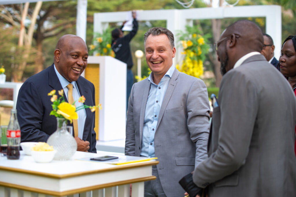 MTN Chairman, Charles Mbiire (L) and Vanhelleputte (C) share a light moment with a guest at Vanhelleputte's farewell party