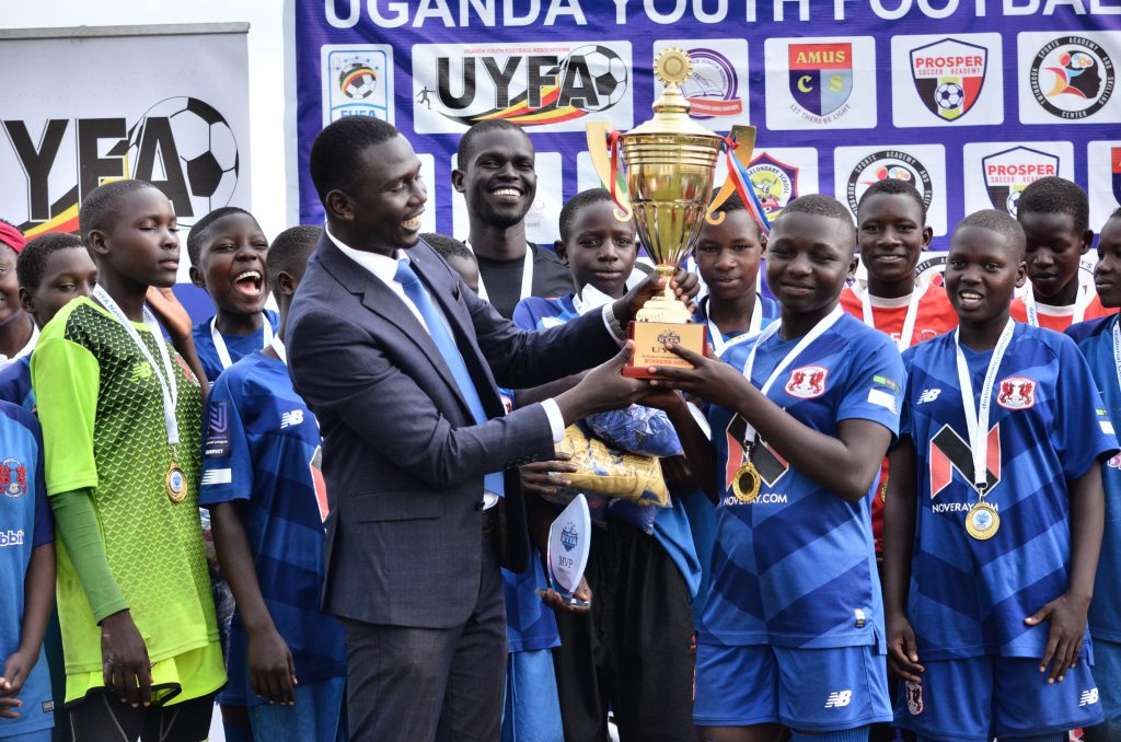 UYFA Chairman Roberts Kiwanuka hands over the girls winners trophy to CBI Sports. (1)