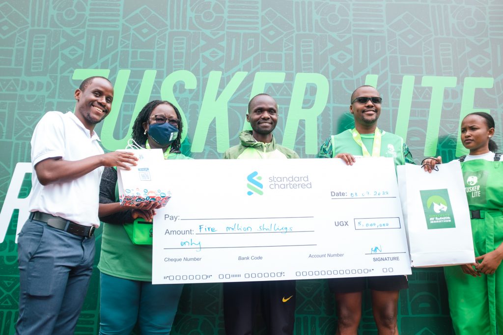 Andiema, middle is flanked by marathon sponsor and partner representatives as he displays a dummy cheque on the podium.