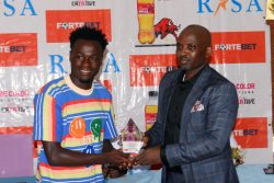 Bunyaga receiving his award from Guest of Honor, Lawrence Muganga