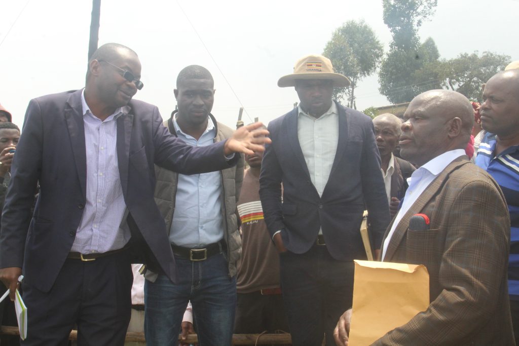 Elly Mucunguzi the Rubanda District Principal Assitant Secretary ( L) explains to Stephen Kamugisha ( R) as Patruick Abanaite the Muko LCIII chairman in hat looks on