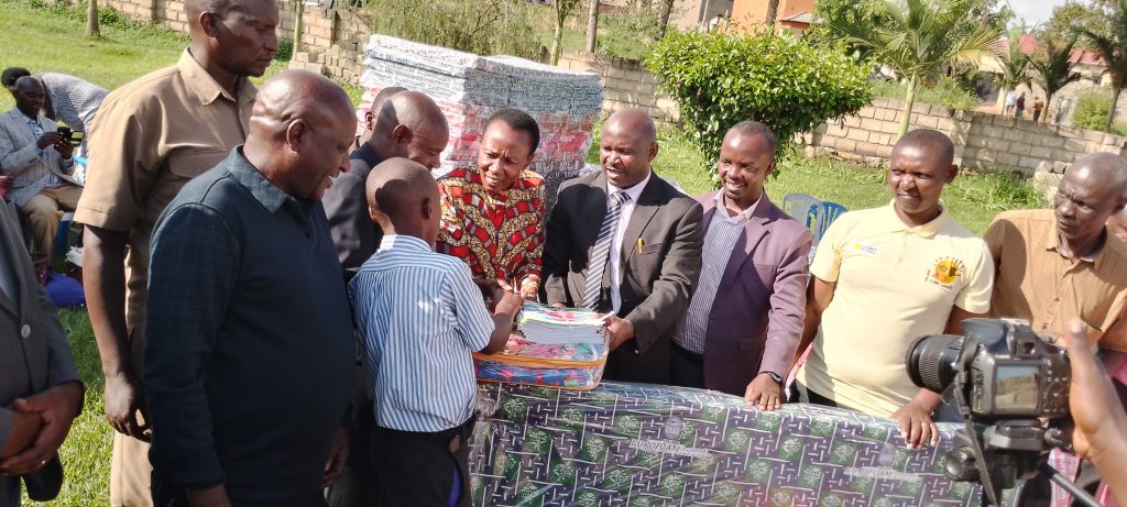 MP Kabasharira and DEO giving out the gifts to one of the pupil who passed in first grade