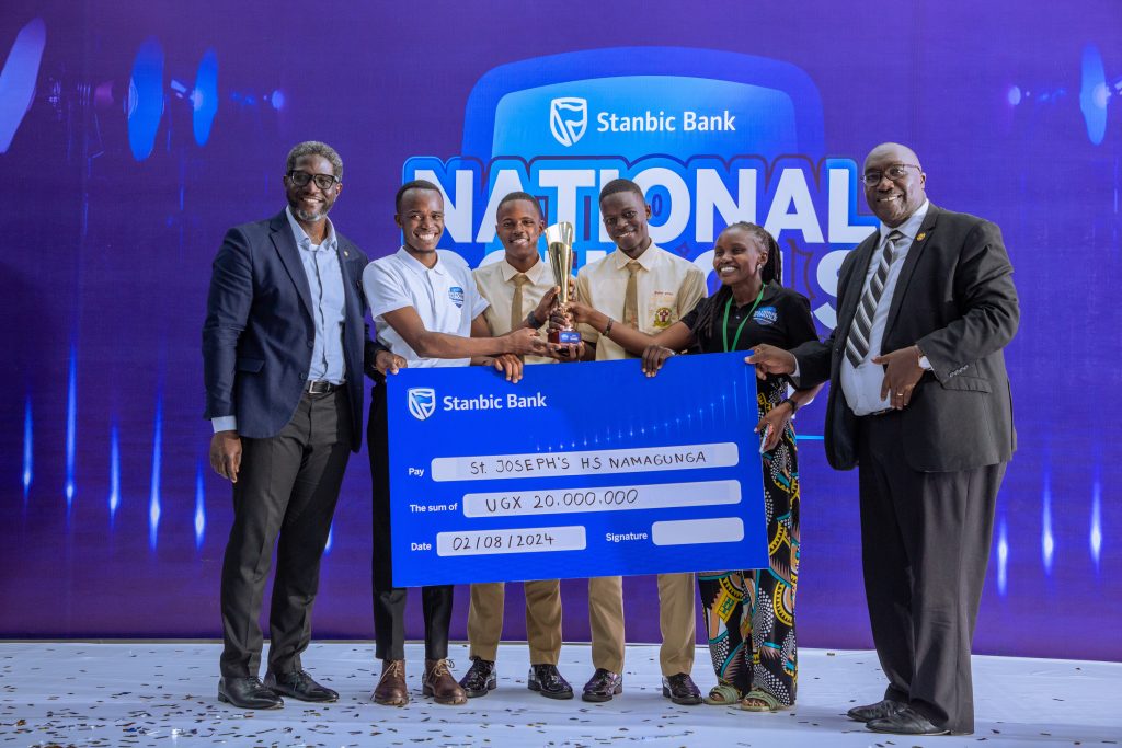 Sam-Mwogeza-the-Stanbic-Bank-Executive-Director-hands-over-a-dummy-cheque-to-St-Josephs-High-School-Namagunga-who-won-in-the-Student-Spark-Category-with-their-Sani-Troll-Project-1024x683