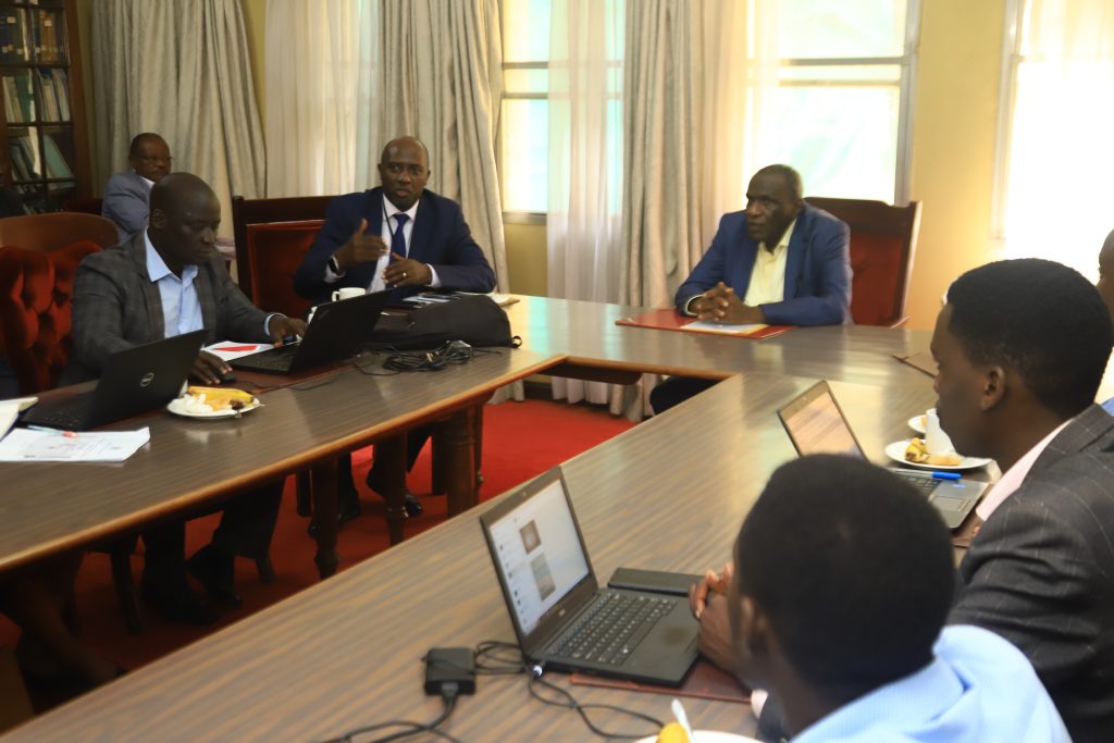 MIU Director Willis Bashaasha explains to PS Hajji Kakande (C) how the reporting system works