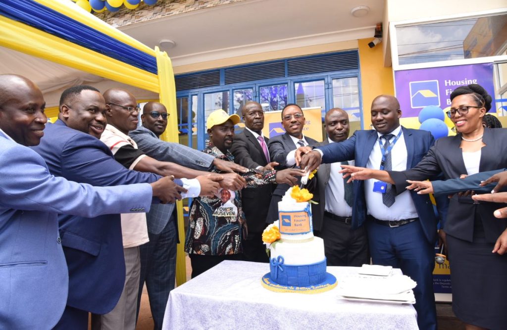 Michael Mugabi, MD of Housing Finance Bank(Center), Bosco Bainamazima, BOU (3rd from right), Nansana Town Clerk, Tandeka Festo and other HFB officials cut cake during the opening of the new branch in Nansana