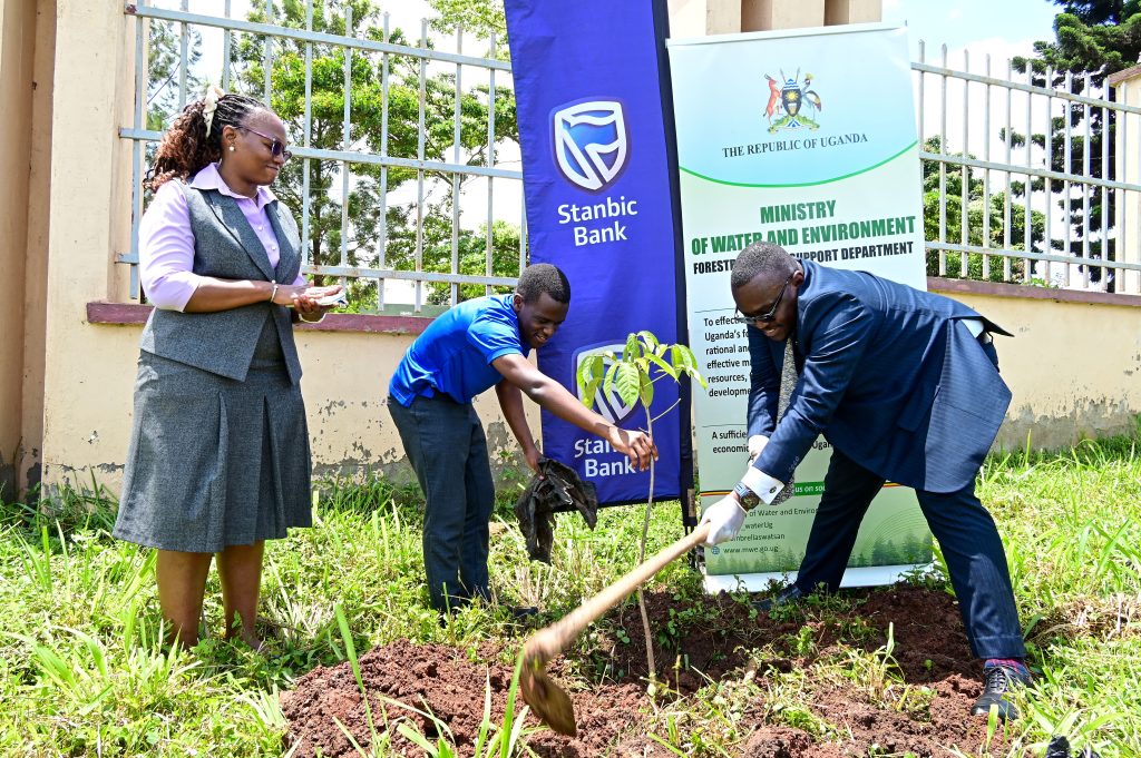Stanbic Bank Executive Head of Business Commercail Banking Tunde Thorpe and Nasuuna Catherine, the undersecretary at the Ministry of Water and Environment taking part in a tree planting activity..