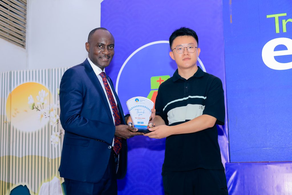 Centenary Bank Executive Director Business, Joseph Kiwanuka Balikuddembe, (L), handing over an appreciation plaque to one of the Chinese Businessmen.