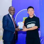 Centenary Bank Executive Director Business, Joseph Kiwanuka Balikuddembe, (L), handing over an appreciation plaque to one of the Chinese Businessmen.