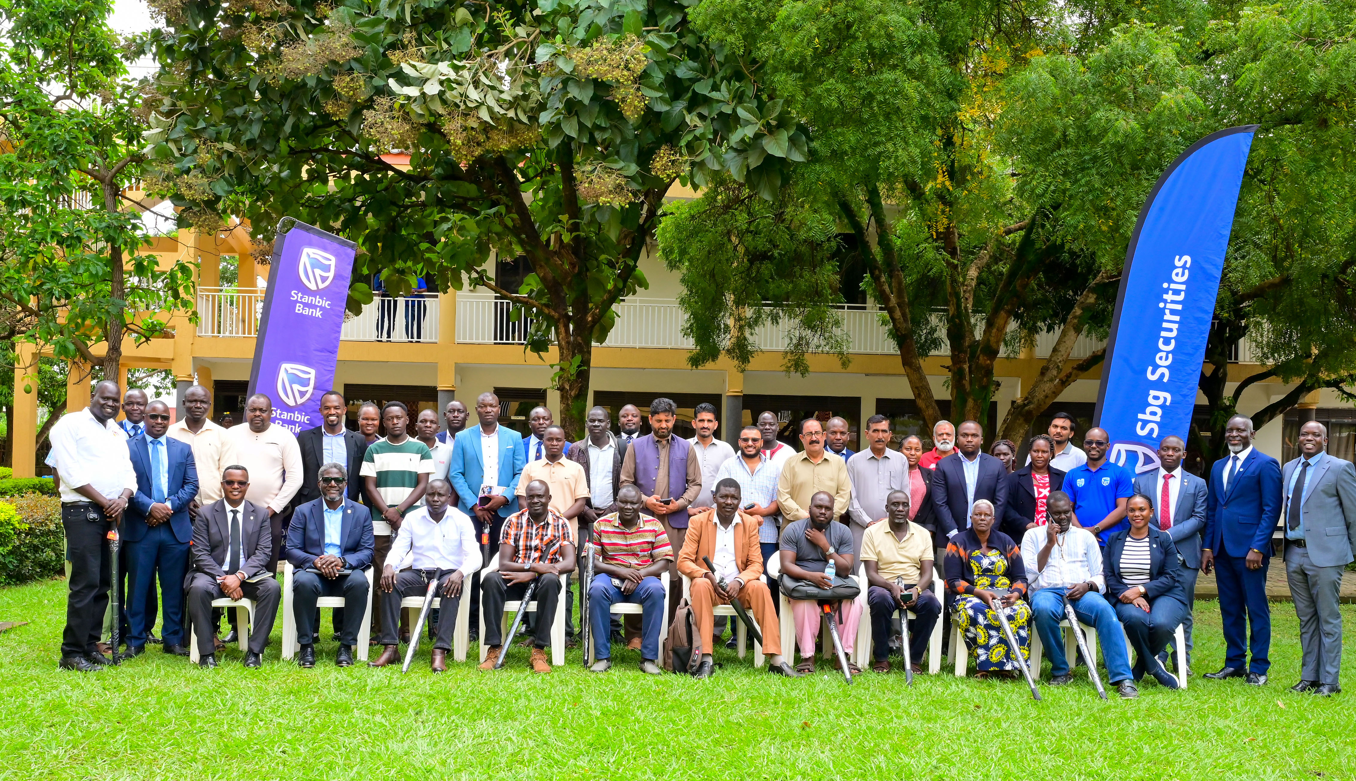 Sam Mwogeza, Executive Director Stanbic Bank Uganda pose for a group photo with some of the customers in Lira.JPG